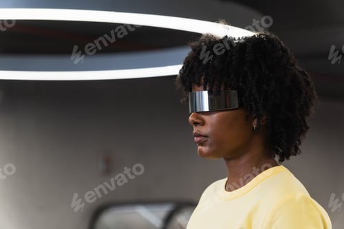 Preview: Young woman with futuristic cyber glasses standing under modern ring lamp
