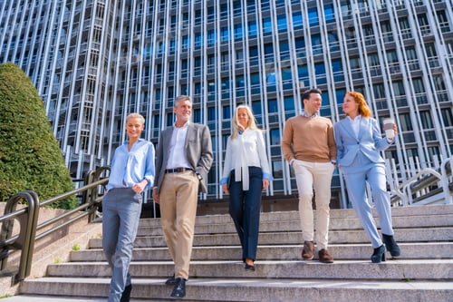 Preview: Cheerful group of coworkers outdoors in a corporate office area walking down some stairs going work
