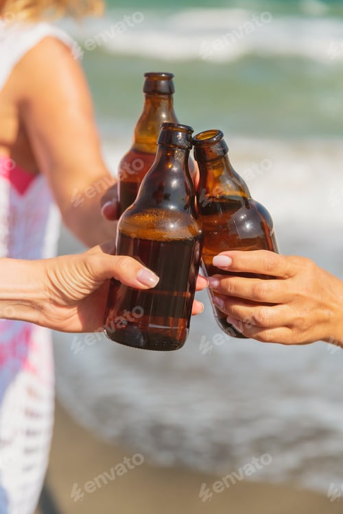 Preview: Group toast with beer bottles on a sunny beach