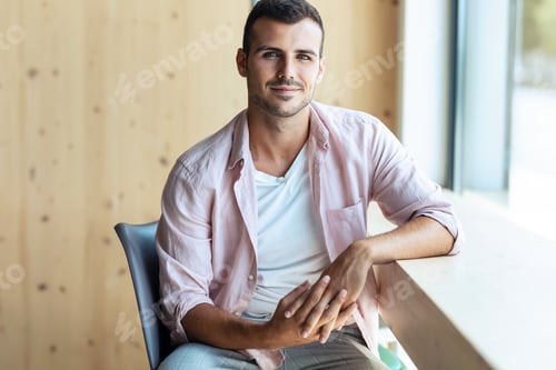 Preview: Confident man looking at camera while in a coworking place.