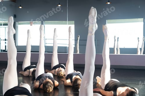 Preview: Group of ballet dancers laying on the floor with their legs pointed up