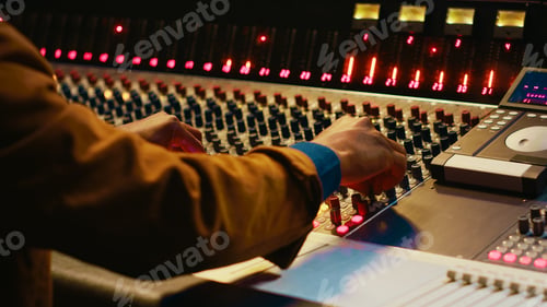 Preview: Audio technician producing new music at mixing console in control room