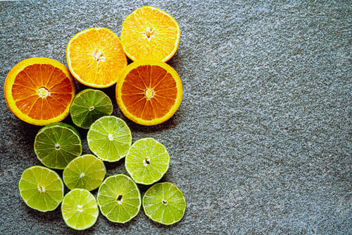 Preview: Various citrus and juicy lime and orange slices on gray stone background from above. Place to insert