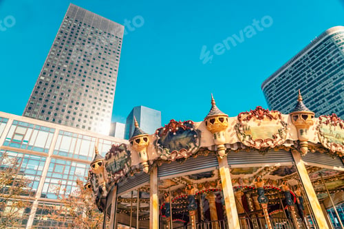 Preview: A carousel in the foreground with intricate details under a clear blue sky, flanked