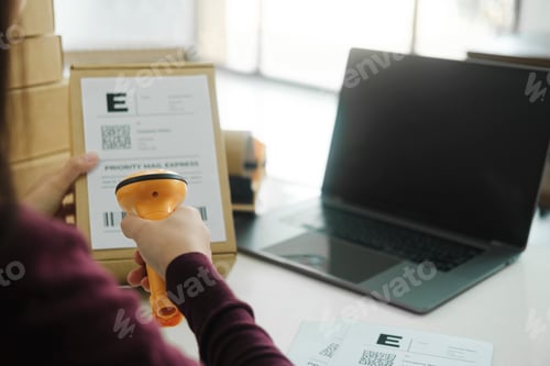 Preview: Female online business owner scan shipping label on parcel.