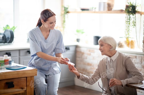 Preview: Nurse giving pills to aged woman after lunch