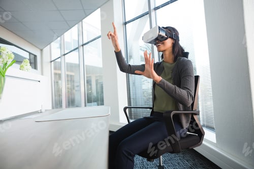Preview: Female executive using virtual reality headset at desk