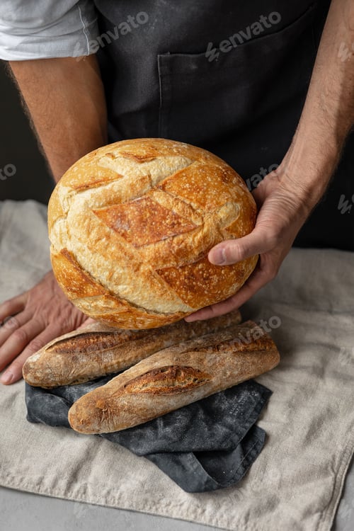 Preview: a white european man holding a cut delicious and crispy baguette or loaf