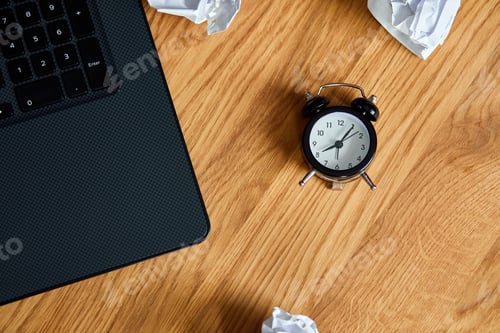 Preview: Top view of wooden office desk with clock,, notebook, crumpled paper balls