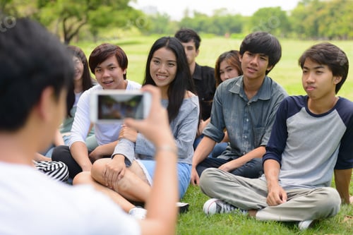 Preview: Happy young group of friends taking picture with phone together at the park