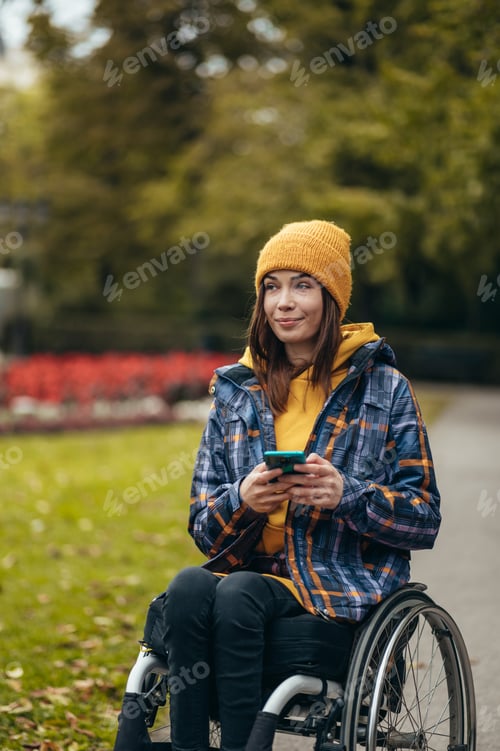 Preview: Woman in wheelchair using a smartphone while out in the city park