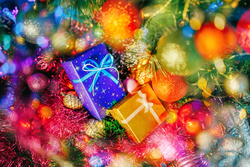 Preview: A beautiful gold colored gift box with a bow lies among tinsel and Christmas decorations