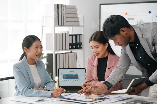 Preview: Marketing team analyzing charts on paperwork using laptop in office