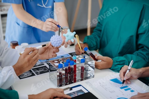 Preview: Medical team having a meeting with doctors in white lab coats and surgical scrubs seated at a table
