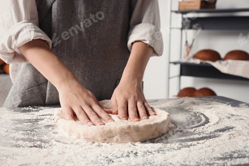 Preview: Woman kneading dough at table in kitchen, closeup