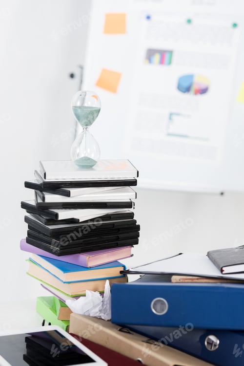 Preview: hourglass on stack of DVDs and folders in light business office
