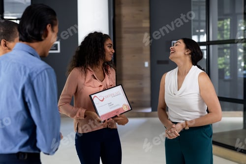 Preview: In modern office, woman holding certificate celebrating achievement with colleagues
