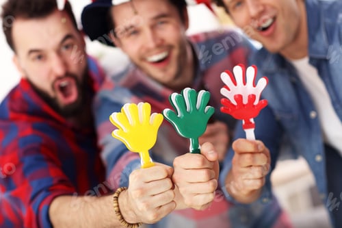 Preview: Happy male friends cheering and watching sports on tv