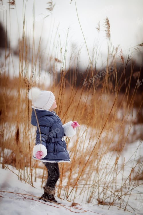 Preview: Kid child in white knitting hat near winter lake , bluring