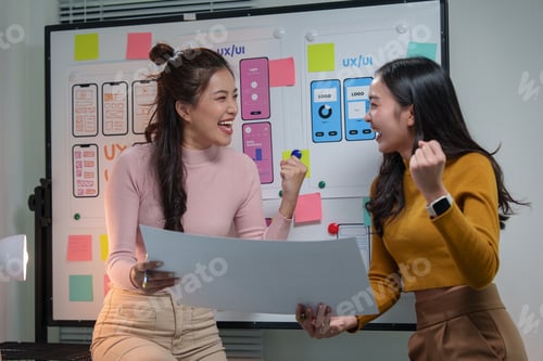 Preview: Two enthusiastic asian ux ui designers are celebrating a successful project, expressing joy and acco