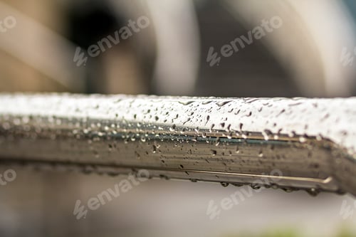 Preview: Close-up of horizontal metal wet shiny pipe with big rain water drops on blurred abstract background