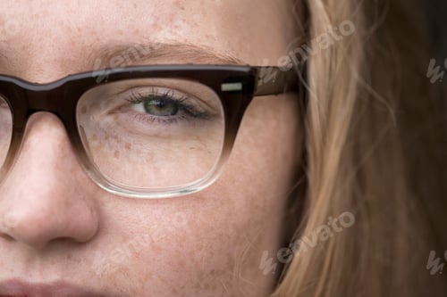 Preview: Close-up of young woman with freckles wearing eye glasses