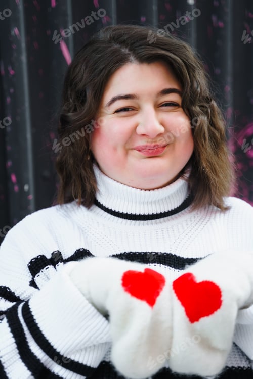 Preview: Smiling plus-size woman wearing a striped sweater with red heart details on sleeves. Standing