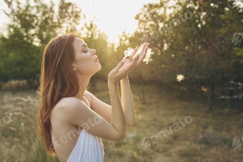 Preview: attractive woman in a white sundress resting in nature at sunset