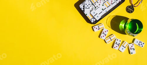 Preview: White domino, winner medal and green drink in a glass on yellow background.