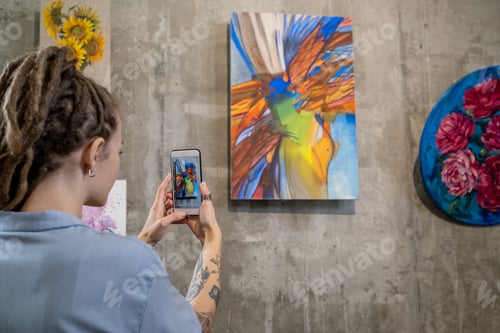 Preview: Contemporary young woman taking photo of abstract painting on wall