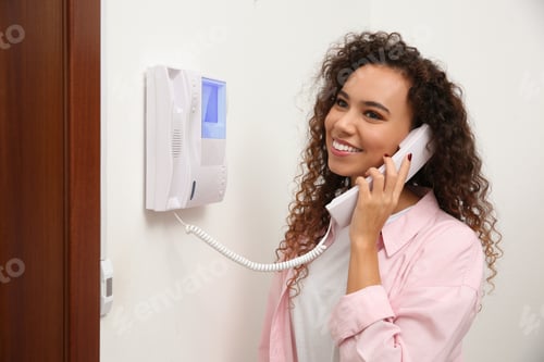 Preview: Young African-American woman answering intercom call indoors