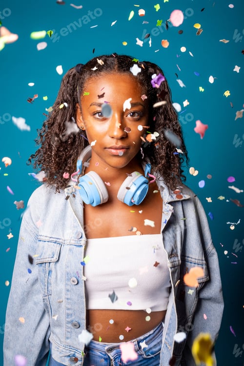 Sad young woman standing and looking at camera with confetti around her