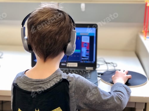 Preview: Child using computer for school with headphones on