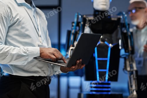 Preview: Engineer using laptop to program robot