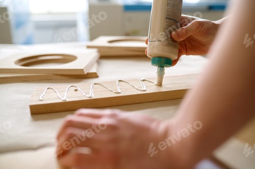 Preview: Closeup carpenter applying glue to board wooden timbers