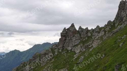 Preview: Picturesque view of the cloudy sky over the rocky mountains covered with grass