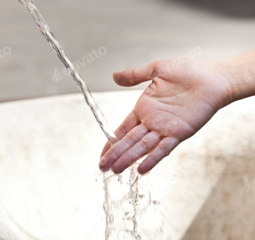 Preview: Hand catching running water from public fountain