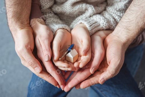 Preview: cropped shot of family holding key from new house in hands