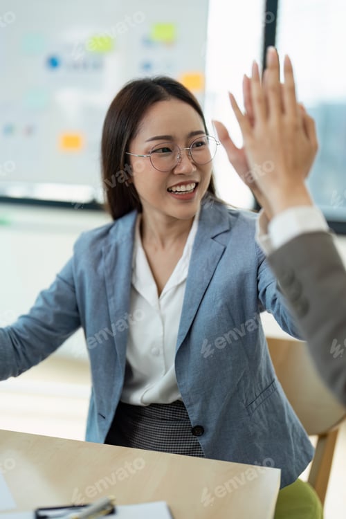 Preview: Businesswoman Celebrating Success with a High Five in a Modern Office Environment