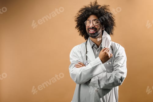 Preview: Happy mature man doctor with face mask in standing in studio, end of coronavirus concept.