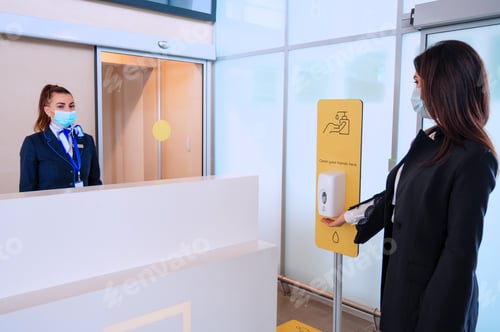 Preview: Passenger sanitizes hands for check-in in front of airport manager by counter