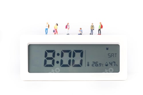 Preview: Closeup shot of little figurines of students standing on a digital alarm clock