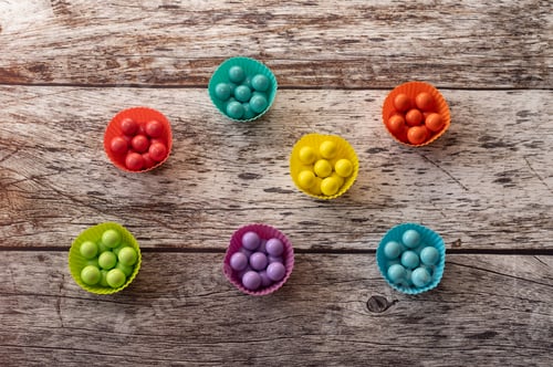 Preview: Colorful Candy in Muffin Cups on Wood Background