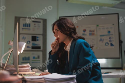 Preview: Woman working overtime concentrating on late night analysis