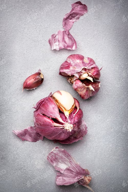 Preview: Fresh purple garlic with husk on gray kitchen table background, top view
