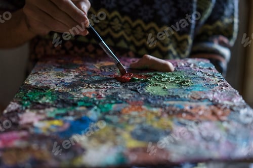 Preview: Male artist mixing oil paint on palette in artists studio, close up detail