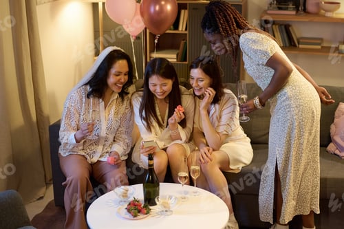 Visualização: Mulheres multiétnicas rindo de fotos e compartilhando macarons durante a festa nupcial