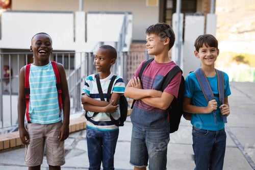 Preview: Group of diverse male students with backpacks smiling while standing at school