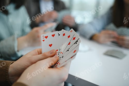 Preview: Friends playing cards at table having fun together