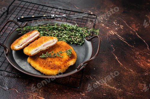 Preview: Cordon bleu chicken fillet cutlet with ham and cheese. Dark background. Top view. Copy space